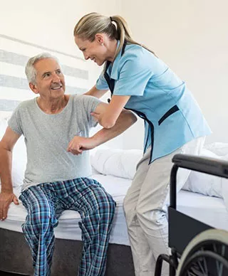 A caregiver helping a senior man up from bed