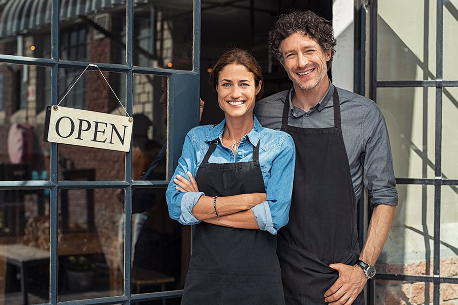 Reviews: Smiling business owners stand in front of their shop